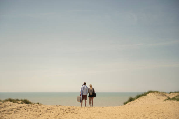 homem e mulher em férias na praia curtindo vista para o mar - mid distance - fotografias e filmes do acervo