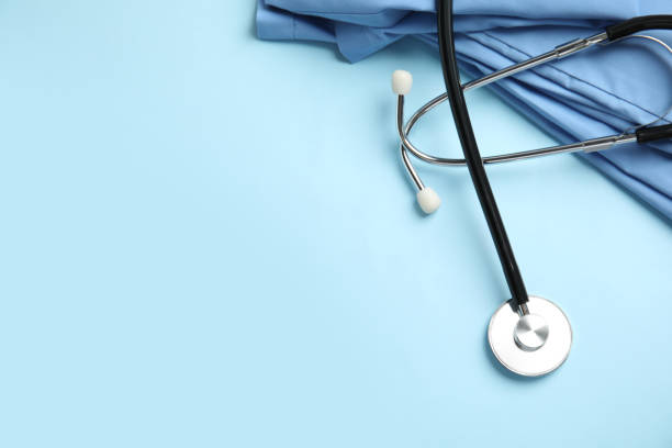 Stethoscope and medical uniform on light blue background, flat lay. Space for text