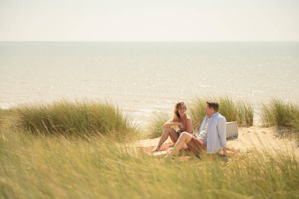 istock Smiling couple in 20s and 30s relaxing on blanket at beach 1325013929