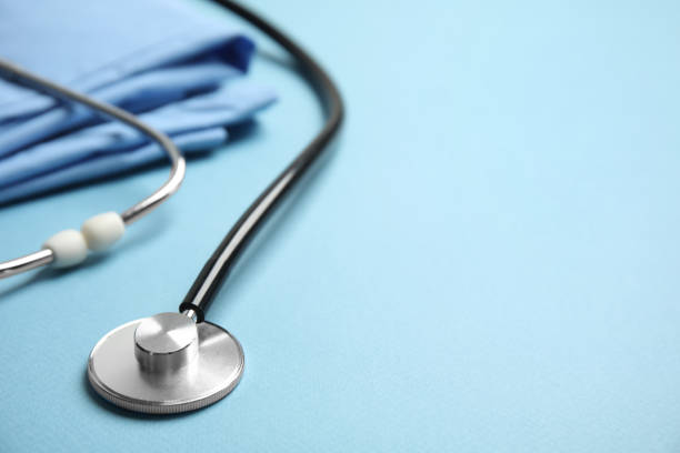 istock Stethoscope and medical uniform on light blue background, closeup. Space for text 1325013942