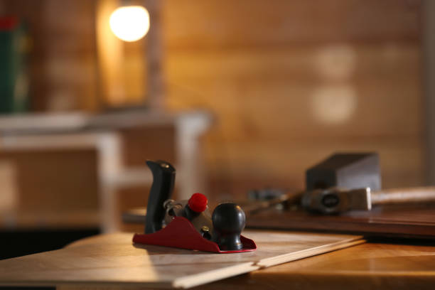 istock Hand plane and wooden plank on table in carpenter's workshop. Space for text 1325013971