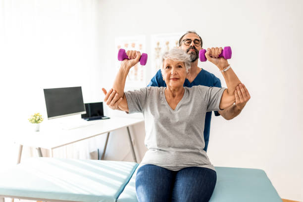 istock Old woman training with physiotherapist using dumbbells 1325013982