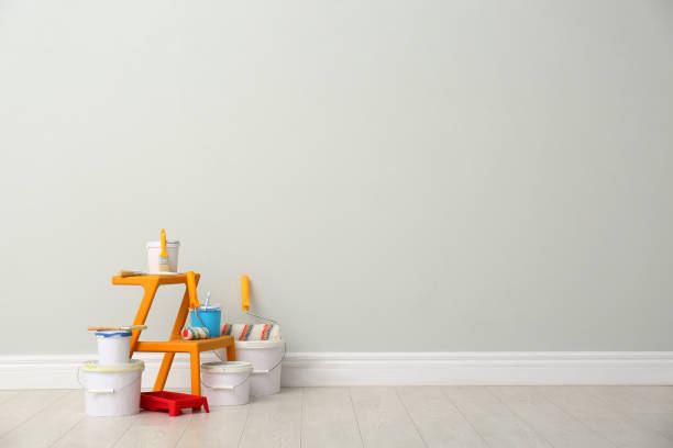istock Decorator's kit of tools and paints near light wall indoors. Space for text 1325014088