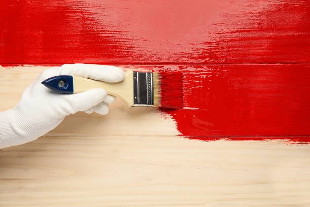 istock Worker in gloves painting wooden surface with red dye, top view. Space for text 1325014713
