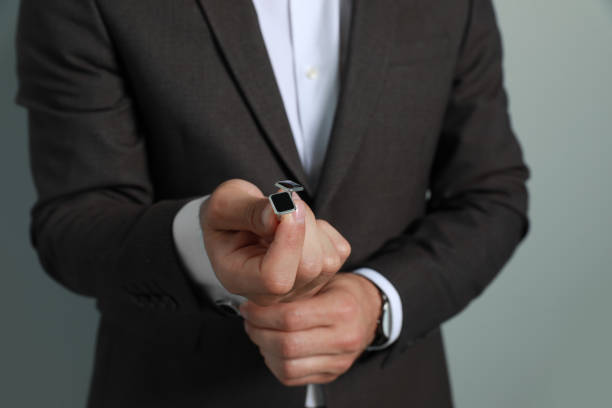istock Stylish man holding cufflinks against grey background, closeup 1325014814
