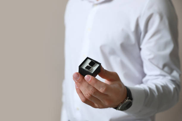 istock Stylish man holding box with cufflinks against beige background, closeup 1325014929