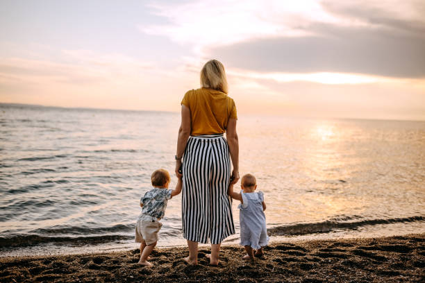 istock Mother with two children enjoying sunset on the beach 1325015869