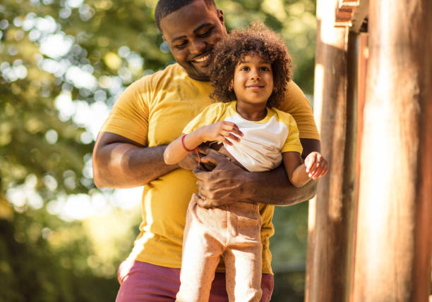 African dad playing with his daughter in playground.