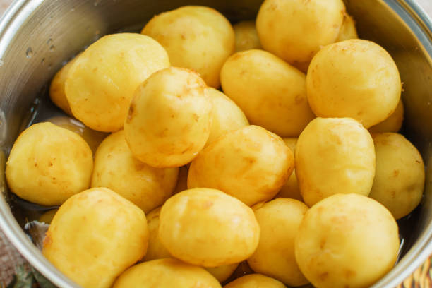 新鮮な皮をむいたジャガイモは鍋にあり、沸騰する準備ができています - young potatoes ストックフォトと画像