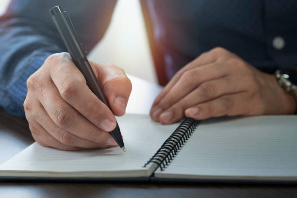 istock Close-up of man hand using writing pen memo on notebook paper or letter, diary on table desk office. Workplace for student, writer with copy space. business working and learning education concept. 1325020319