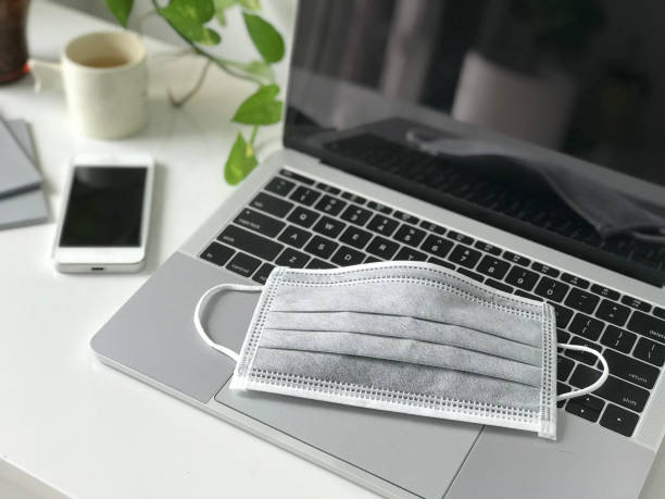 istock Covid-19 Self-isolation work from home. Medical mask on notebook laptop computer home working station. Protection mask anti virus corona n-cov for safety quarantine 1325020496