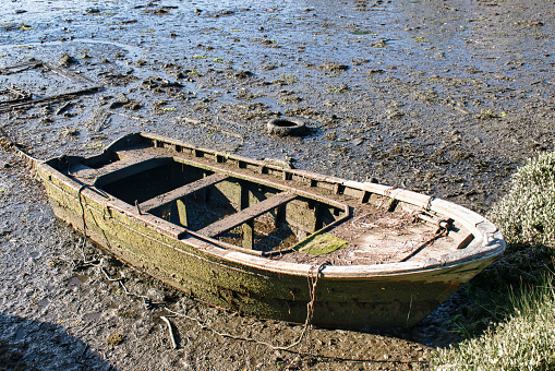 Old and abandoned rowboat stranded on the bank of the mouth of the Verdugo River at low tide in Ponte Sampaio, Pontevedra, Spain