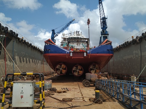 Maritime industry background - Ocean Vessel in a dry dock in shipyard. View from aft, ship with 3 propellers.