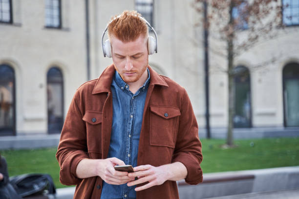 istock Man looking at the smartphone and listening music while standing 1325023650