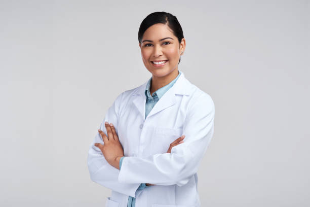 retrato cropped de uma jovem cientista atraente de pé com os braços cruzados em estúdio contra um fundo cinza - jaleco de laboratório - fotografias e filmes do acervo