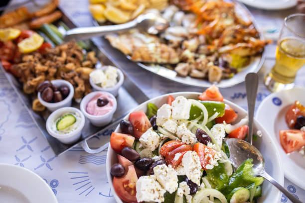 Greek salad in bowl and seafood on table Greek salad, fresh vegetables, feta cheese and black olives in bowl and seafood on table greek food stock pictures, royalty-free photos & images