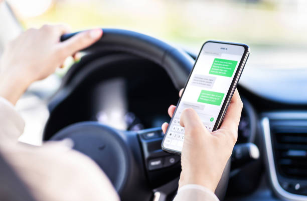 conducir el coche y usar el teléfono. conductor distraído enviando mensajes de texto con teléfono celular móvil. mujer irresponsable revisando mensajes sms con smartphone en el tráfico. concepto de accidente automovilístico. - driving car distracted accident fotografías e imágenes de stock