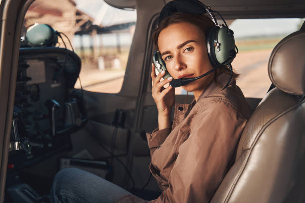 charming young woman sitting inside plane cockpit - aviator glasses audio imagens e fotografias de stock