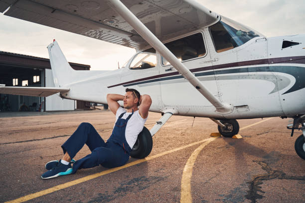 istock Handsome male worker sitting on asphalt near airplane 1325031978