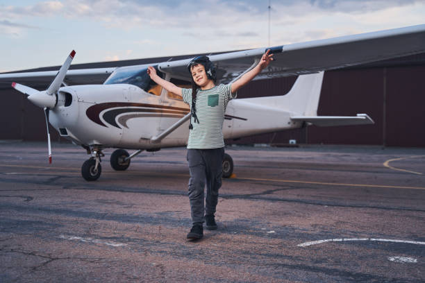 istock Cheerful boy in aviation hat standing near plane at aerodrome 1325032013