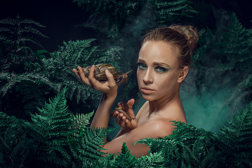 Beautiful Mother Nature female figure with giant snails in a fern natural green setting