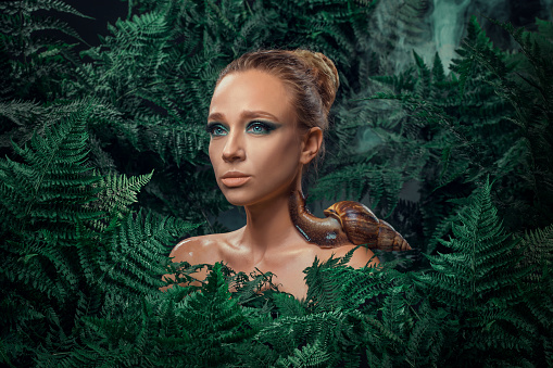 Beautiful Mother Nature female figure with giant snails in a fern natural green setting