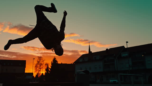 Young man doing back flip on street