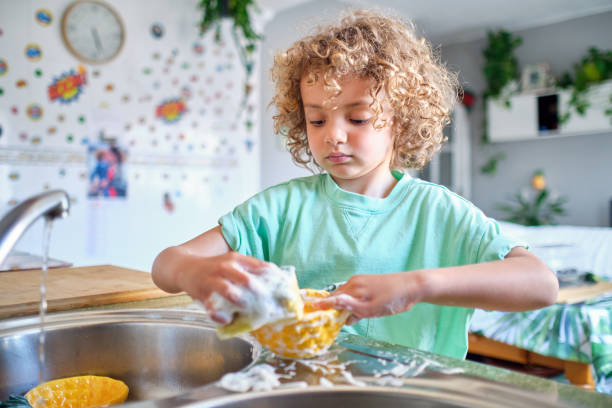 enfant hispanique lavant la vaisselle du déjeuner avec de l’eau et du savon - chores photos et images de collection