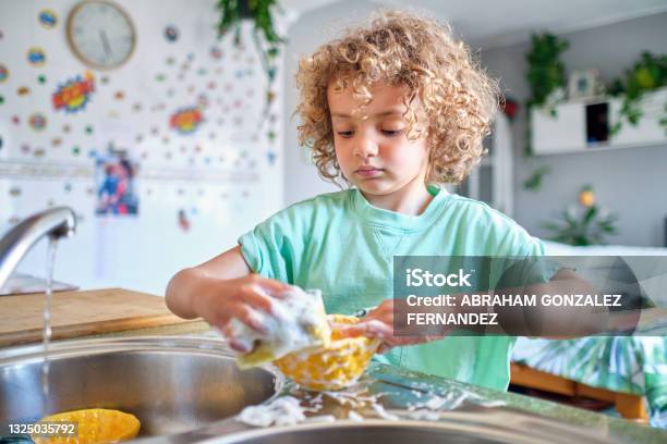 Hispanic Child Washing Lunch Dishes With Soap And Water Stock Photo - Download Image Now