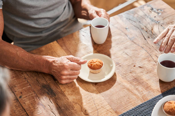 istock Man holding a cup of tea and preparing to eat the cupcake while having breakfast 1325036129