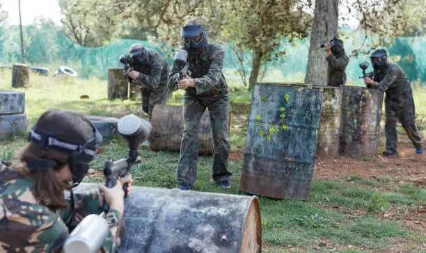 Photo of Team of friends paintball players in  camouflage playing together in battle in forest