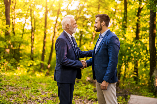 Two businessman making an agreement about environment and shaking hands in nature.