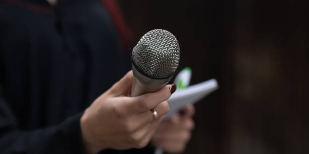 istock Journalist in action at news conference, holding microphones and writing notes 1325041021