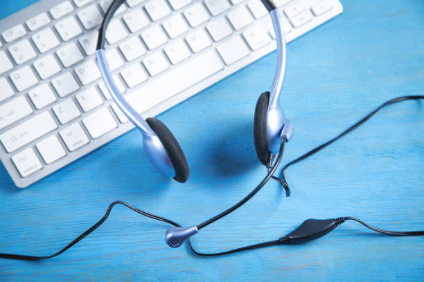 istock Customer service headset and computer keyboard on the blue background. 1325041959