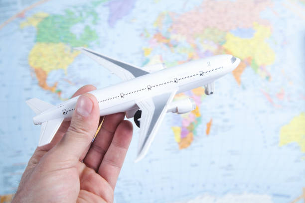 istock Male hand holding airplane on world map. Travel 1325041982