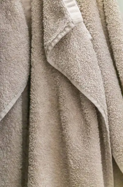 Hanging terry cotton towel, bathroom background, close up terry towel in neutral beige nature colors
