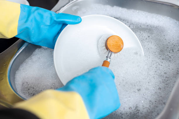 istock Hands in protective glove washing dishes 1325043488