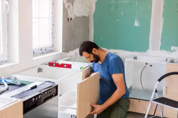 Mature man  installing furniture in domestic kitchen