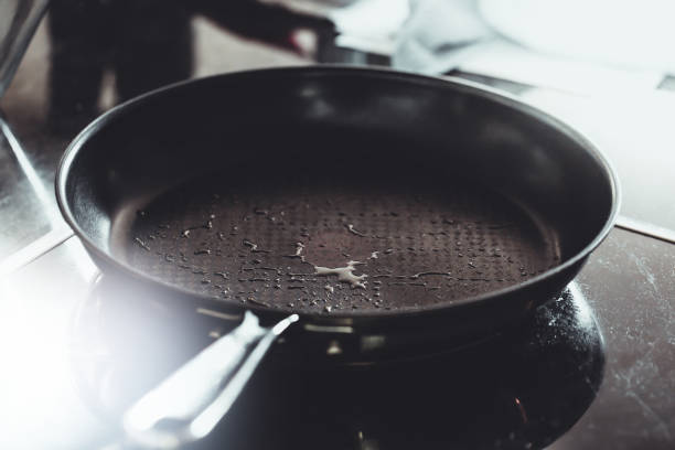 óleo ou manteiga ficando aquecido em uma frigideira antiaderente ou frigideira, cozinha chefs - non stick - fotografias e filmes do acervo