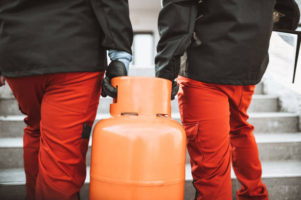 flüssiggasspeicherarbeiter, die gasflaschen auf der treppe tragen - benzinkanister stock-fotos und bilder