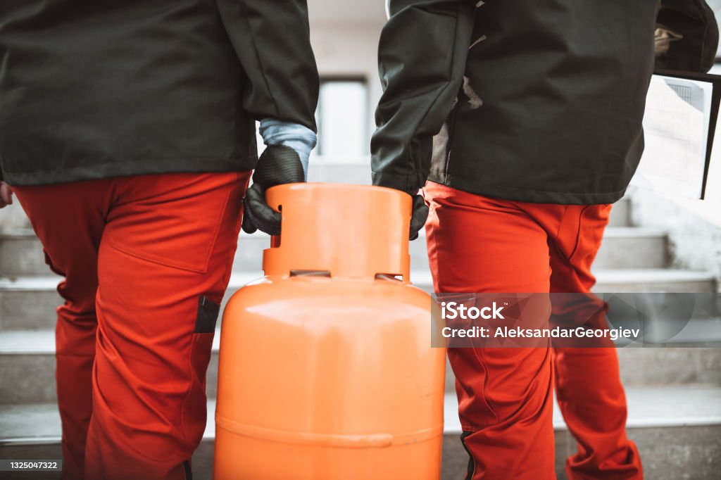 Liquefied Gas Storage Workers Carrying Gas Cylinder On Staircase Natural Gas Stock Photo