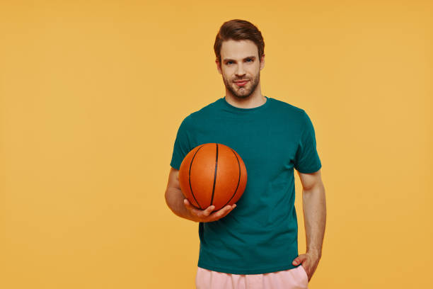 istock Handsome young man holding basketball ball and looking at camera 1325049242