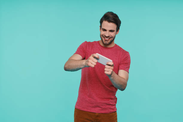 istock Handsome young smiling man in casual clothing using smart phone 1325050560