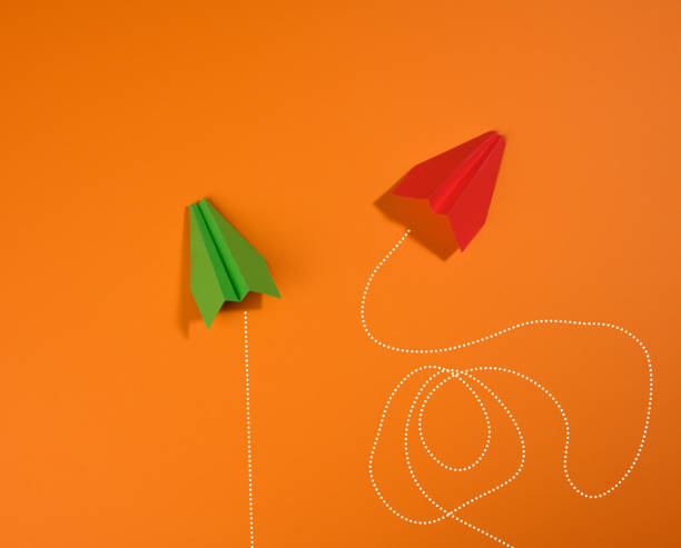 istock two paper airplanes with different trajectory of movement on an orange background 1325051519