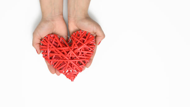 istock two female hands hold a red wicker heart on a white background 1325052461