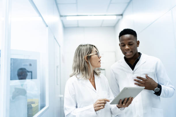 colleghi che utilizzano tablet digitale in laboratorio - teamwork medical research science women foto e immagini stock