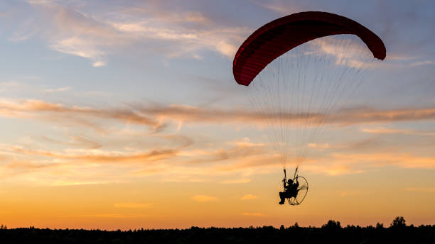 istock Powered paragliding pilot silhouette with back-mounted motor (paramotor) during sunset 1325054509