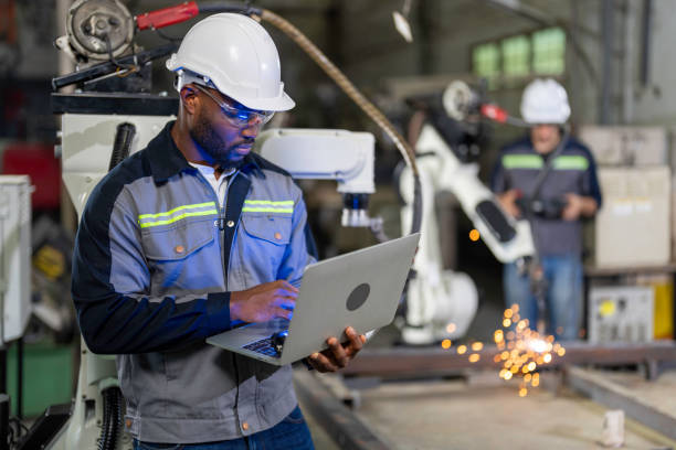 African Mechanical engineer doing maintenance the robotic welding machine. African Mechanical engineer working for maintenance or repairing robotic welding machine in factory. Maintenance and repairing work in modern industry concept. manufacturing occupation stock pictures, royalty-free photos & images