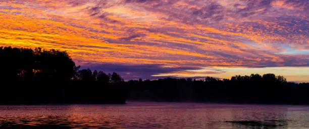 early morning or late evening dramatic sky over forest lake or river, summer panoramic landscape