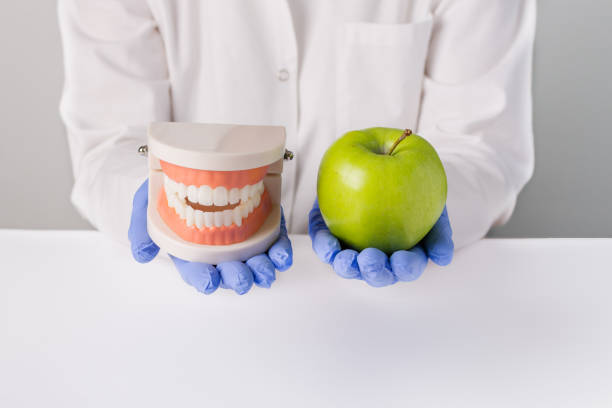 istock Dentist holding jaw teeth model and green apple 1325061716